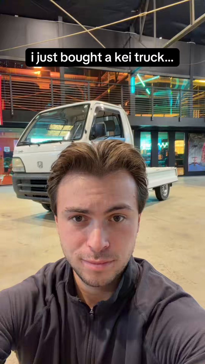A selfie in front of a white Honda kei truck parked indoors, captioned "i just bought a kei truck...". Photo from the launch post.