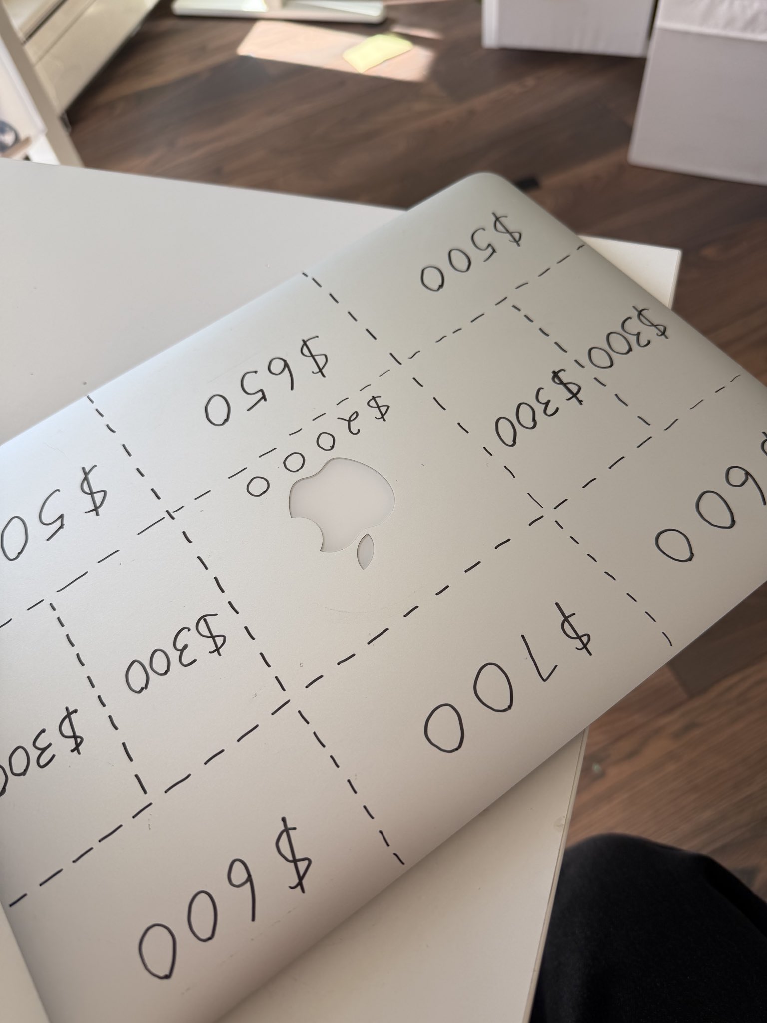 Angel’s MacBook lid with a dashed sticker grid and hand-written prices from $300 to $2,000. Photo from the launch post.